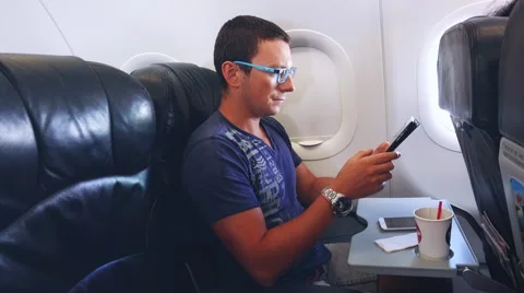 Young handsome businessman with tablet sitting inside an airplane. Young male Stock Footage 59740074