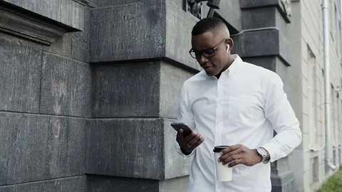 Young handsome businessman using mobile phone in the city. Video stock 79983399
