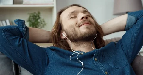 Young handsome caucasian guy with long hair in denim shirt is resting lying on Stock Footage 147050533