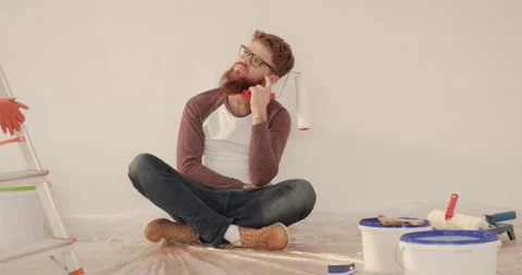 Young handsome caucasian man with beard and glasses sitting on the floor with Stock Footage 144629693