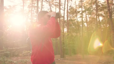 Young handsome Caucasian man in red jacket standing alone in woods and uses Stock Footage 147068432