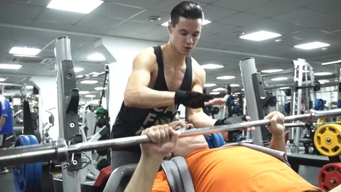 Young handsome couch helps funny fat man to put an empty neck from a bar 스톡 동영상 96820678