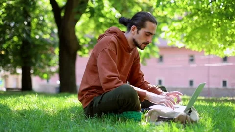 Young handsome freelance man using modern laptop sitting in sunny green park enj 스톡 동영상 139145366