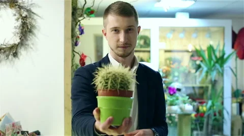 Young handsome guy in a black jacket is turning around and showing cactus. Stock Footage 62926456
