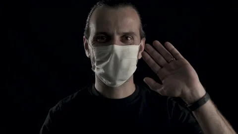Young handsome guy with face mask is hand weaving on black background, studio Stock Footage 133882465
