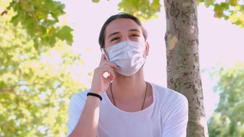 Young handsome guy with face mask talking on the phone outside. Stock Footage 136426070