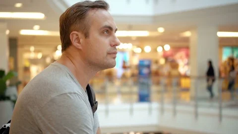 Young handsome guy in grey t-shirt standing in shopping mall. Shopping Stock Footage 75467616