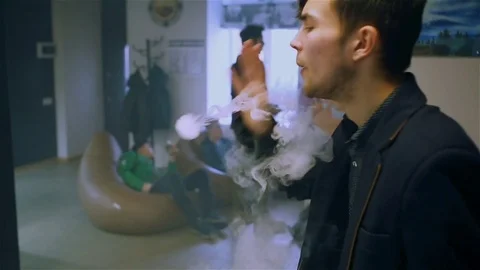 Young handsome guy lets rings out of steam Stock Footage 73027607