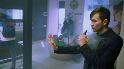 Young handsome guy lets rings out of steam Stock Footage 73027623