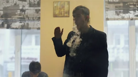 Young handsome guy lets rings out of steam Stock Footage 73027695