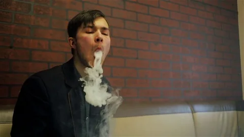 Young handsome guy lets rings out of steam Stock Footage 73027697