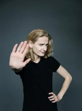 Young handsome guy with long blonde hair holds a hand in protest covering his Stock Photos