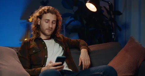 Young handsome guy looking and touching screen while using smartphone Stock Footage 129261491