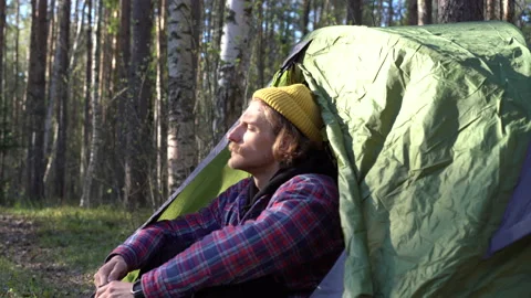 Young handsome guy with a mustache and a beard prepares a tent and a sleeping Stock Footage 130195914