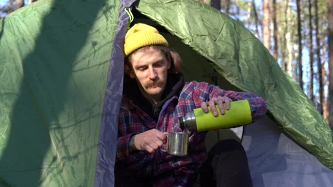 Young handsome guy with a mustache and a beard prepares a tent and a sleeping Stock Footage 130196342