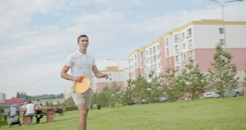 Young handsome guy playing frisbee with his family actively throws a plate of Stock Footage 152935259