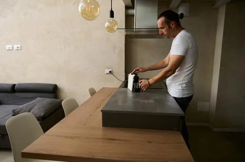 Young handsome guy preparing his morning coffee using a capsule coffee mach.. Stock Photos