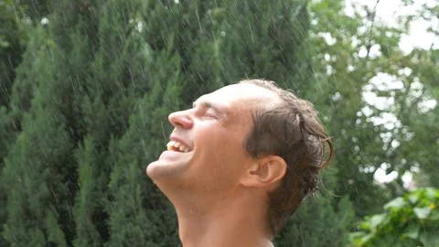 A young handsome guy in the rain. drops of water fall on his face. close-up 4k Stock Footage 91887750