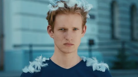 Young handsome guy removing feathers from his hair and shoulders. Stock Footage 68657471