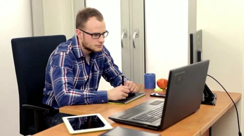Young handsome guy sitting behind the desk and using his two computers Stock Footage 49058222