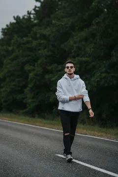 A young handsome guy with a small beard in a white jacket and dark glasses is Stock Photos