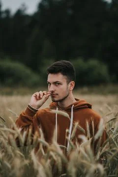 A young handsome guy with a small beard in a brown jacket in the middle of the Stock Photos