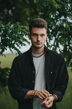 A young handsome guy with a small beard in a black shirt looks at the camera Stock Photos