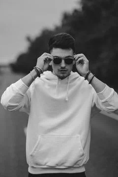 A young handsome guy with a small beard in a white jacket and dark glasses is Stock Photos
