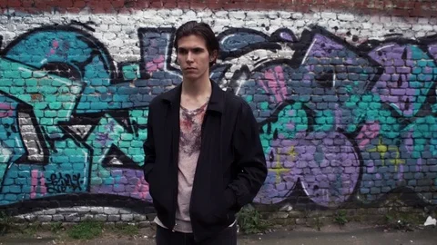 Young handsome guy standing by the graffiti wall. Urban lifestyle Stock Footage 80008432
