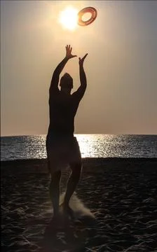 Young handsome guy throws a disc on a sandy beach Stock Photos
