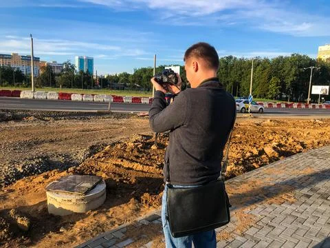A young handsome guy in a warm jacket is taking pictures. subject shooting at Stock Photos