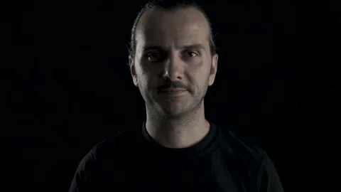 Young handsome guy is wearing face mask in studio shot, black background. Pro Stock Footage 133882831