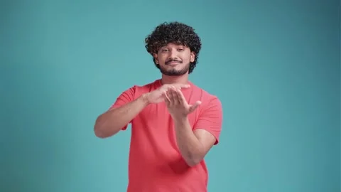 Young handsome Indian man with beard in coral t-shirt on blue studio background Stock Footage 238615655