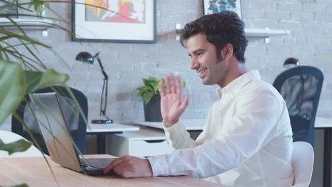A young, handsome indian man waves and is making a video call to relatives and Stock Footage 137049610