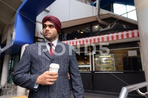 Young handsome Indian Sikh businessman holding disposable coffee cup Stock Photos