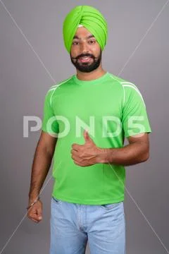 Young handsome Indian Sikh man wearing turban and green shirt Stock Photos