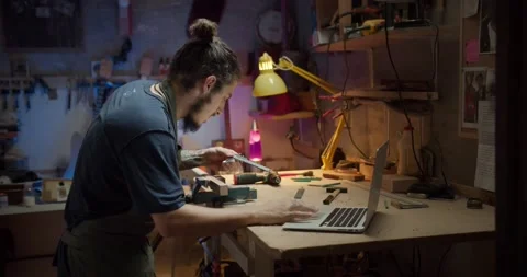 Young handsome luthier beginner searching online using computer how to use Stock Footage 137242913