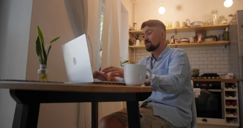 Young handsome man is angry because of failure sitting at the desk in the living Video stock 157651587