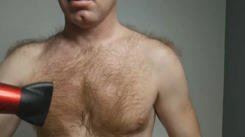 A young, handsome man with a bare torso and raised hairline dries his chest hair Video stock 128326589