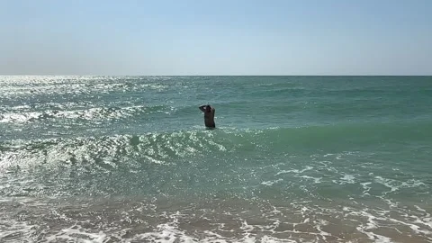 Young handsome man, bathing in the cold sea, trying to enter the water Stock Footage 259465372