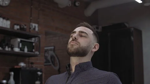Young handsome man with beard admires his reflection in the mirro Stock Footage 112343099