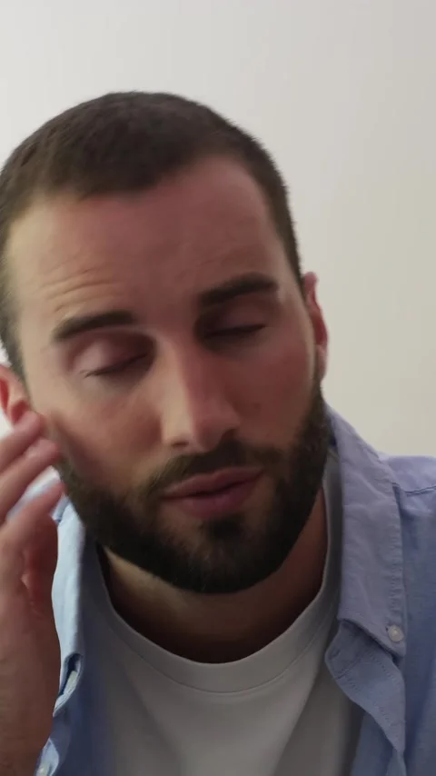 Young handsome man with a beard and blue eyes talking to the camera during an Stock Footage 344782032