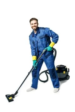 Young handsome man with a beard in a blue working uniform for cleaning rooms  Stock Photos
