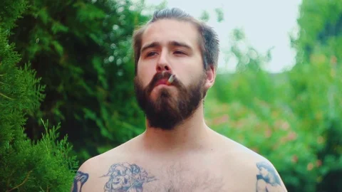 Young Handsome Man with big beard and tattoos smoking cigarette slowly Stock Footage 91385627