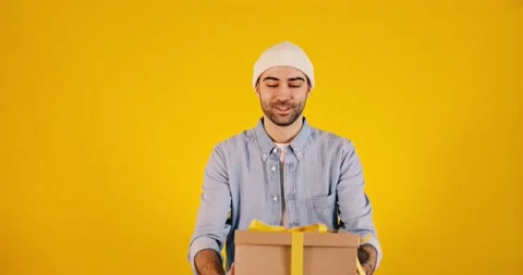 Young handsome man with big present box yellow ribbon. Women's day, 8 March,  Stock Footage 170651868