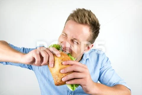 Young handsome man biting fresh sandwich with hunger on isolated white Stock Photos