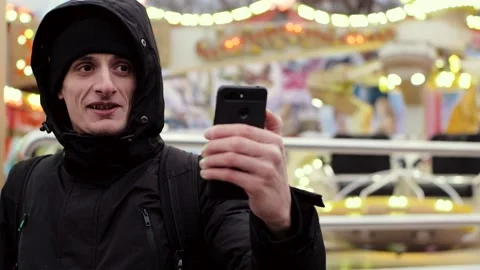 Young handsome man in black jacket and cap having video call on smartphone Stock-Footage 135939910