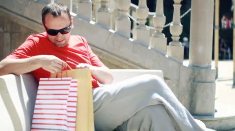 Young handsome man checking his shopping bags after shopping Stock Footage 6141909