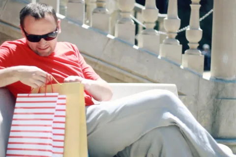 Young handsome man checking his shopping bags after shopping Stock Footage 6142866