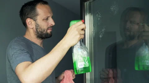 Young, handsome man cleaning a window at his home Stock Footage 64587428